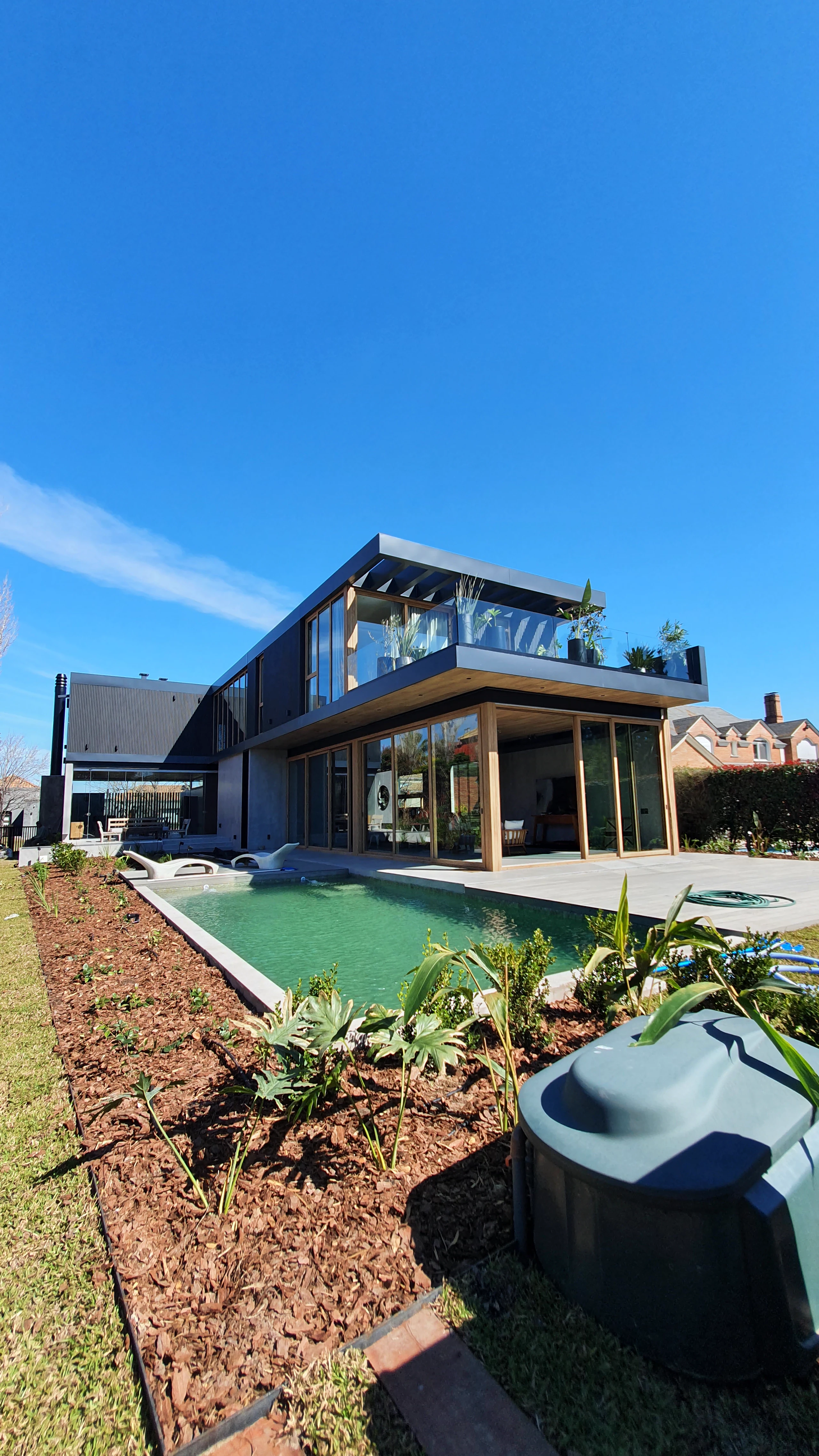 Casa Castores terminada, con piscina, deck y fachada de madera y chapa negra